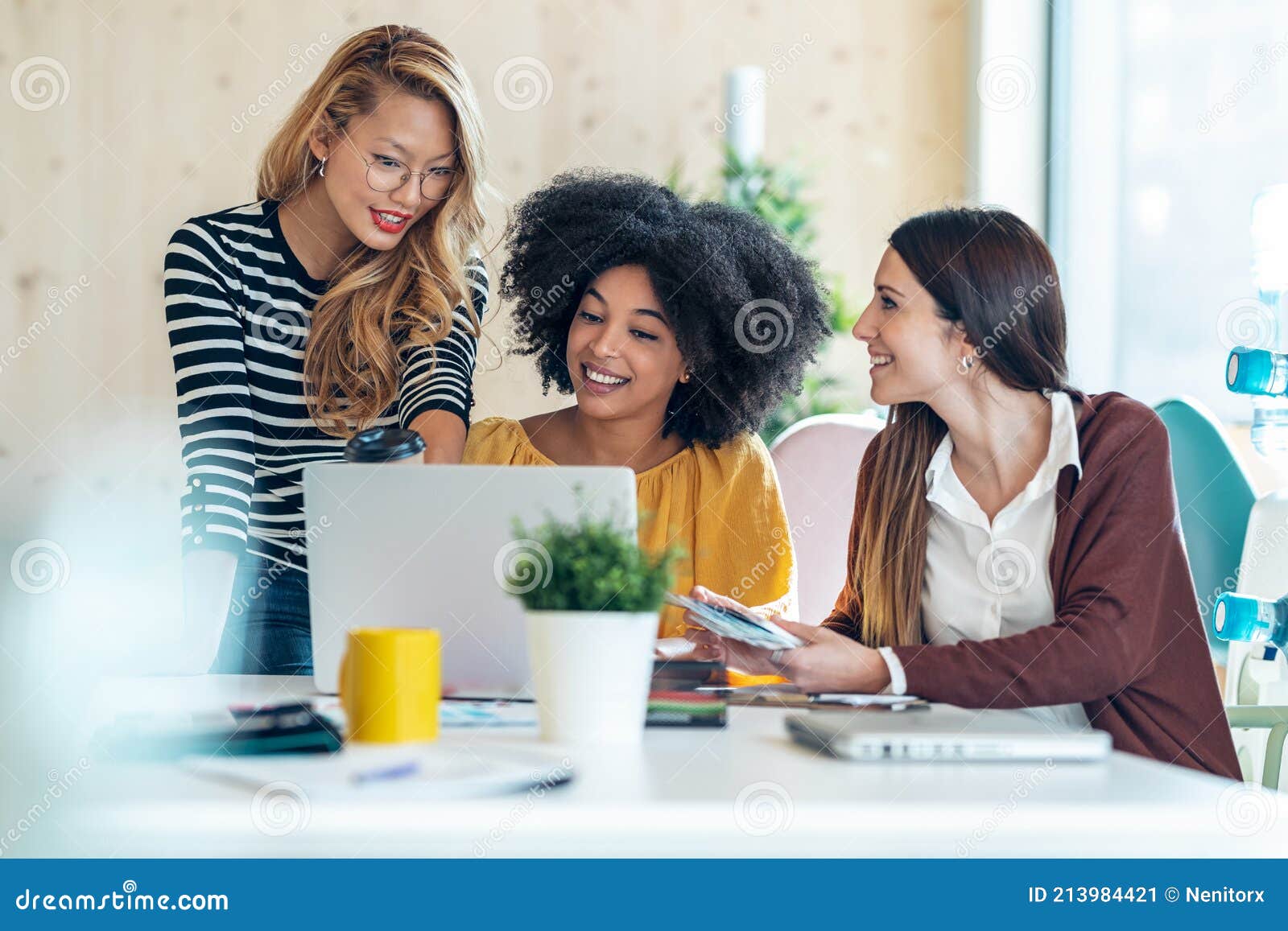 casual multiethnic business women working with laptops while talking of they new projects together in coworking place