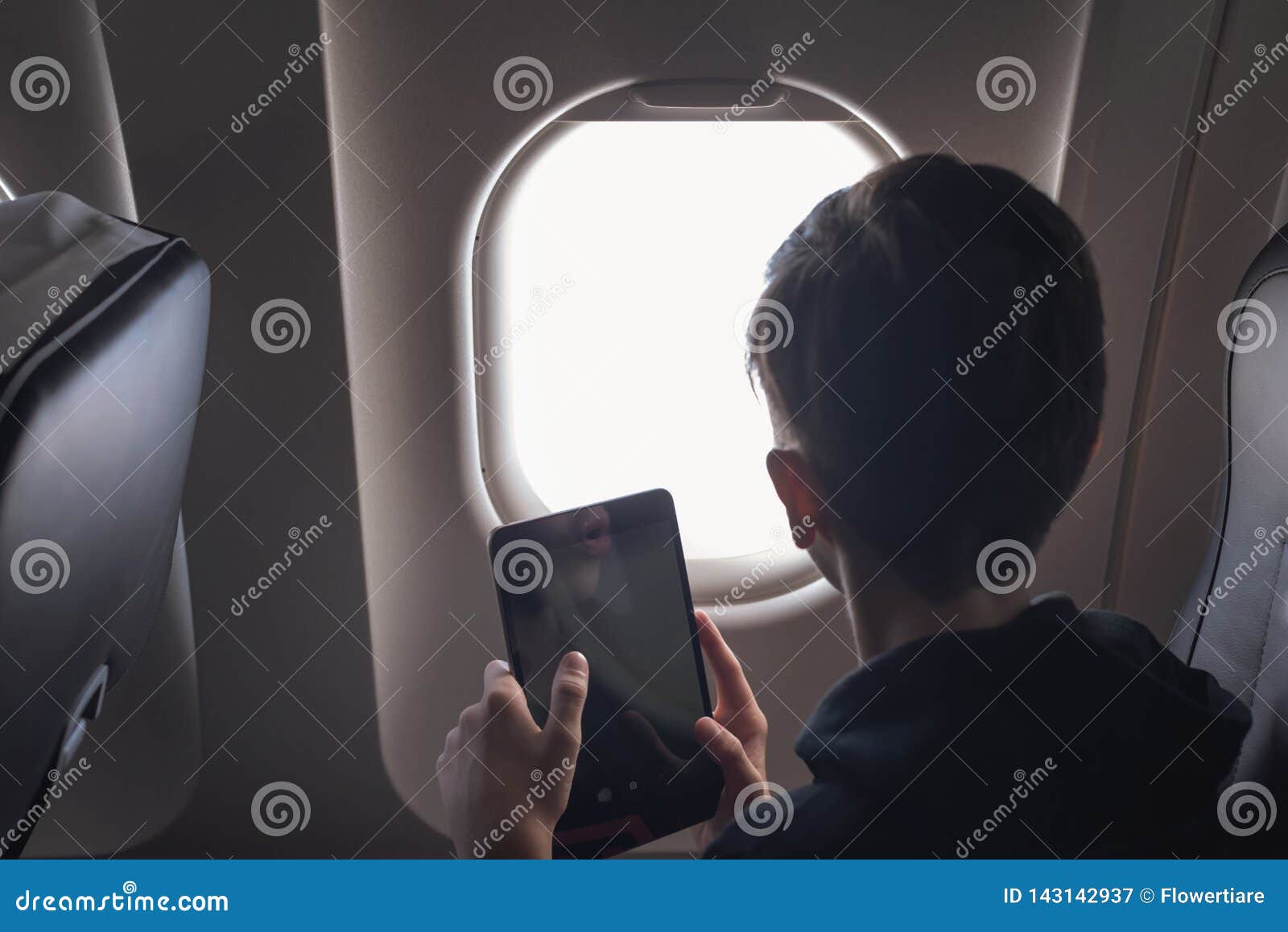 caucasian boy fasten seat belt and using tablet pc and taking picture during air flight.