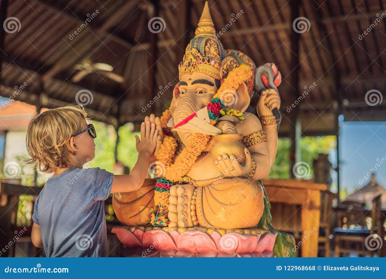 caucasian boy high-five ganesha. meeting western and eastern culture concept. oriental and occidental. traveling to asia with chi