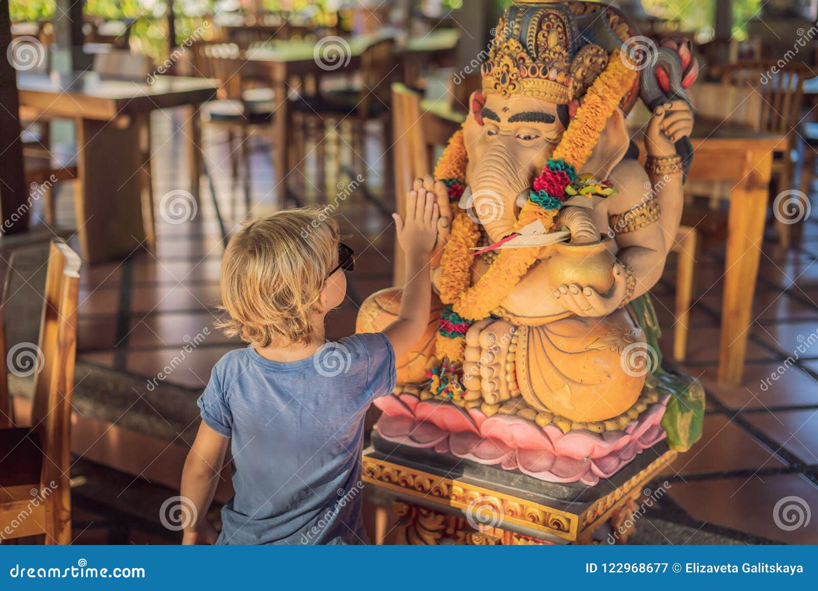 caucasian boy high-five ganesha. meeting western and eastern culture concept. oriental and occidental. traveling to asia with chi