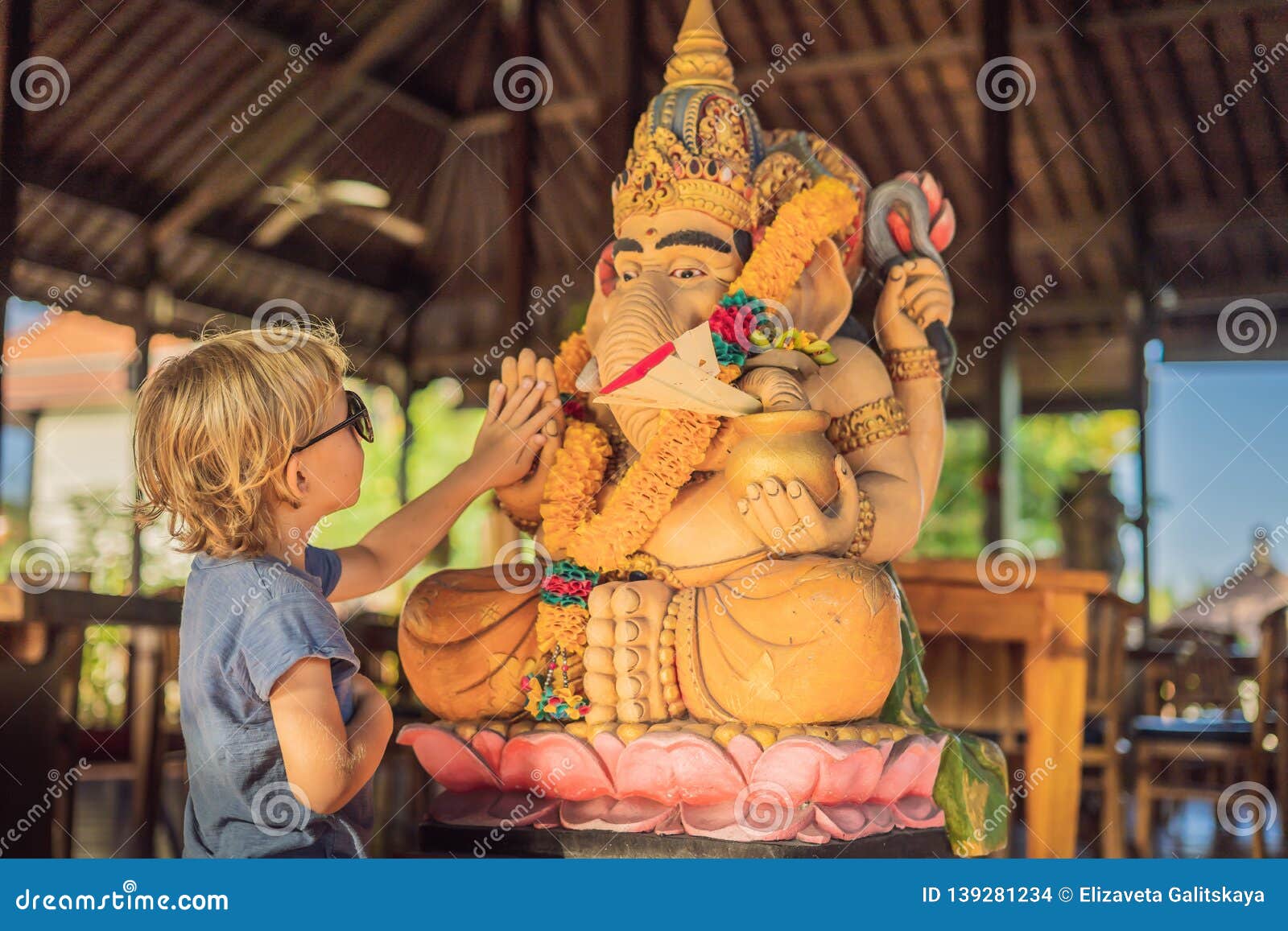 caucasian boy high-five ganesha. meeting western and eastern culture concept. oriental and occidental. traveling to asia