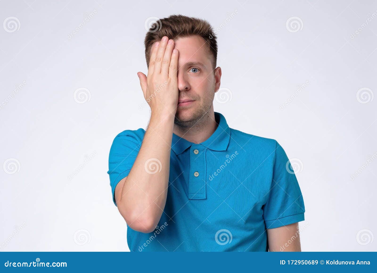 caucasian casual man closes one eye hand, passing through eyesight test