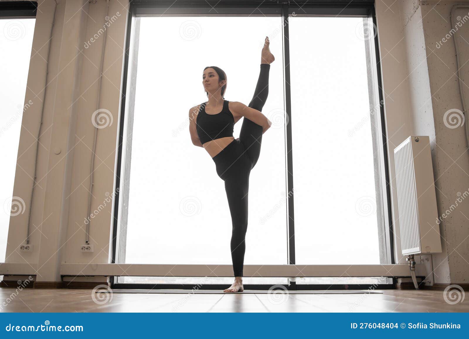 female yogi performing variation of trivikramasana posture