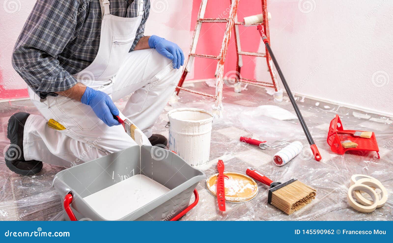 House Painter Worker at Work in the Construction Site. Building Stock