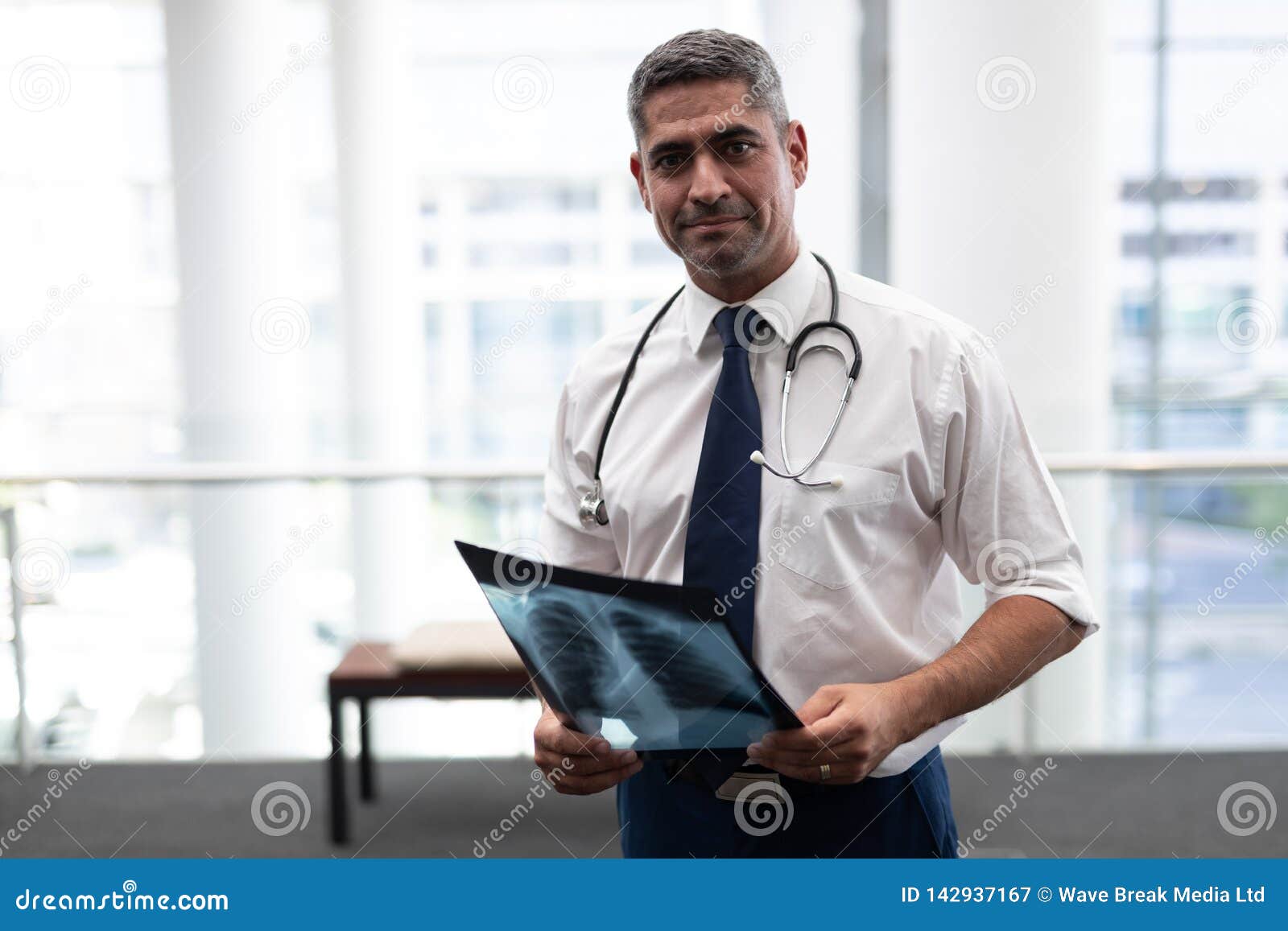 Caucasian Male Doctor With X Ray Looking At Camera In Clinic Stock
