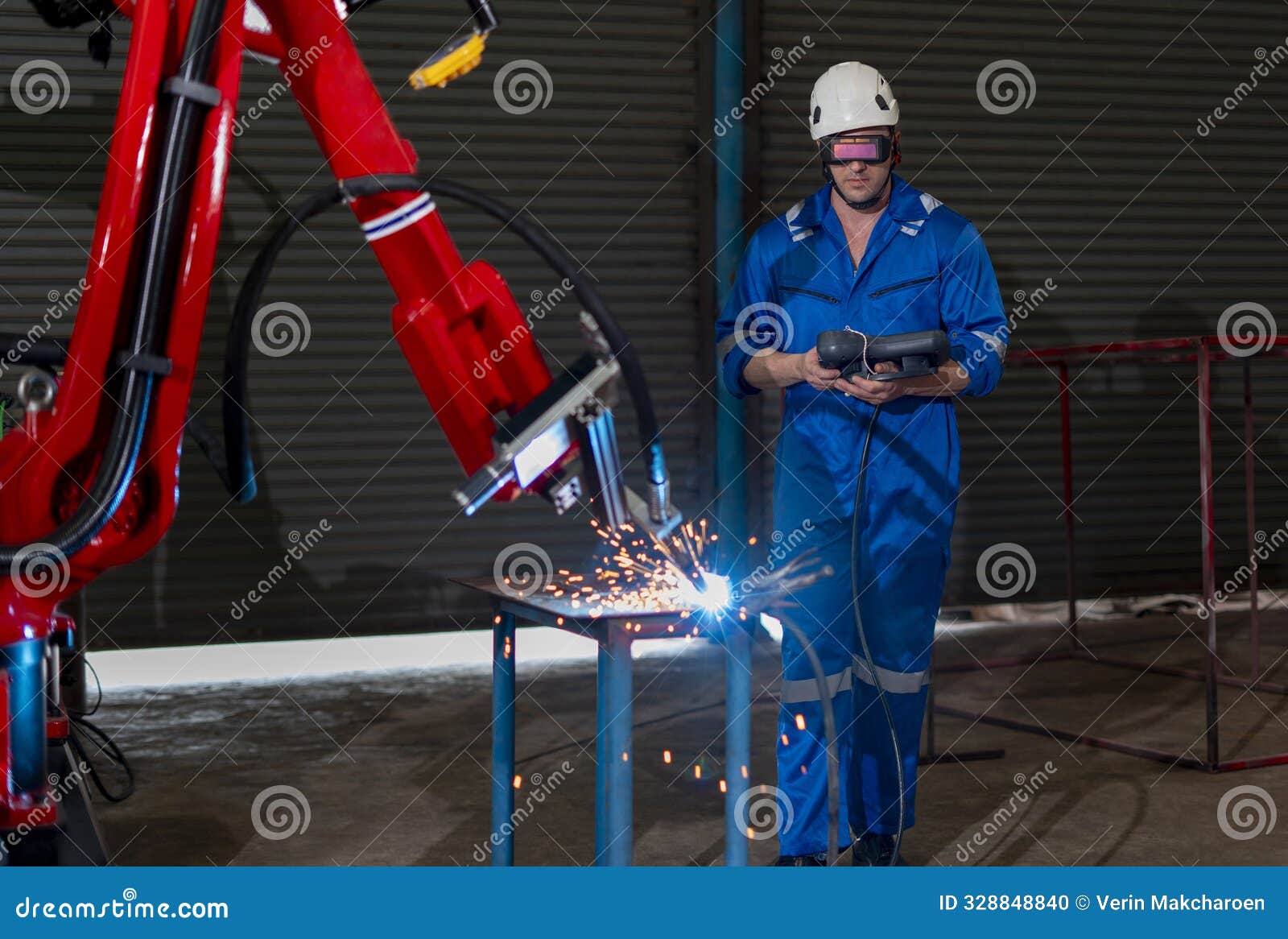 caucasian male in full safety gears holding remote control a robot arm welding machine and check robot readiness