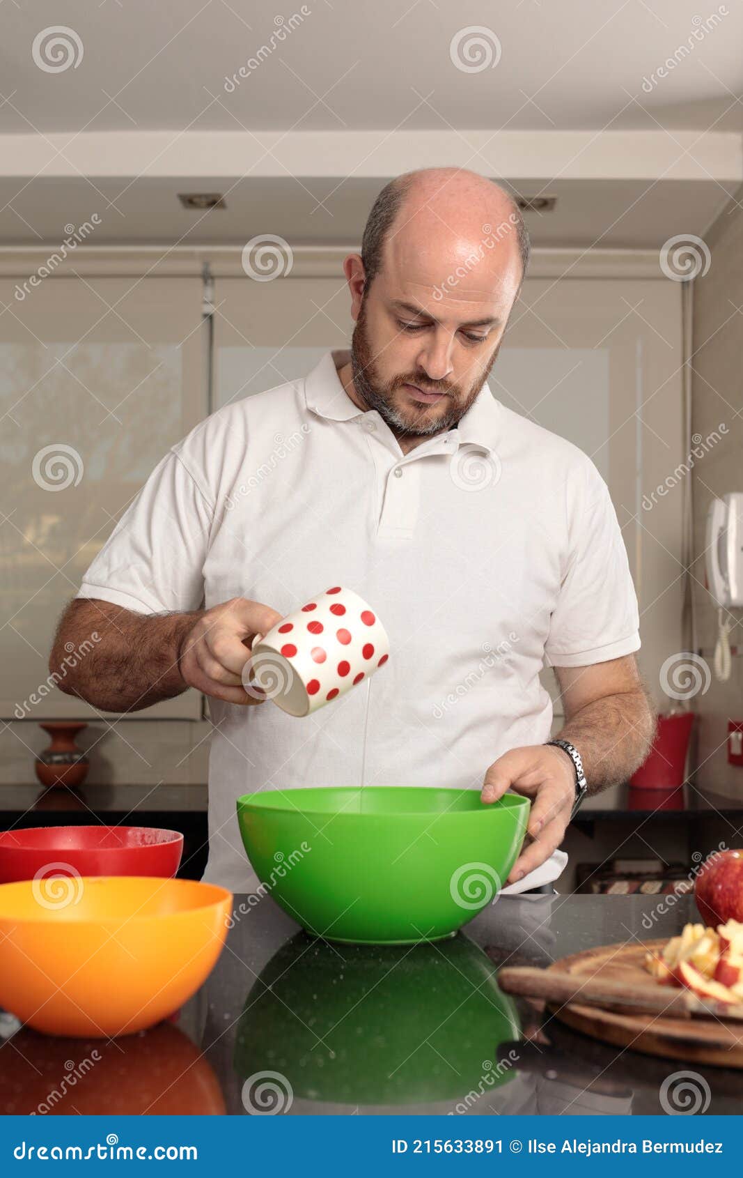 caucasian man, between 30-39 years old, with cup in hand adding ingredients in a bowl, to prepare a cake