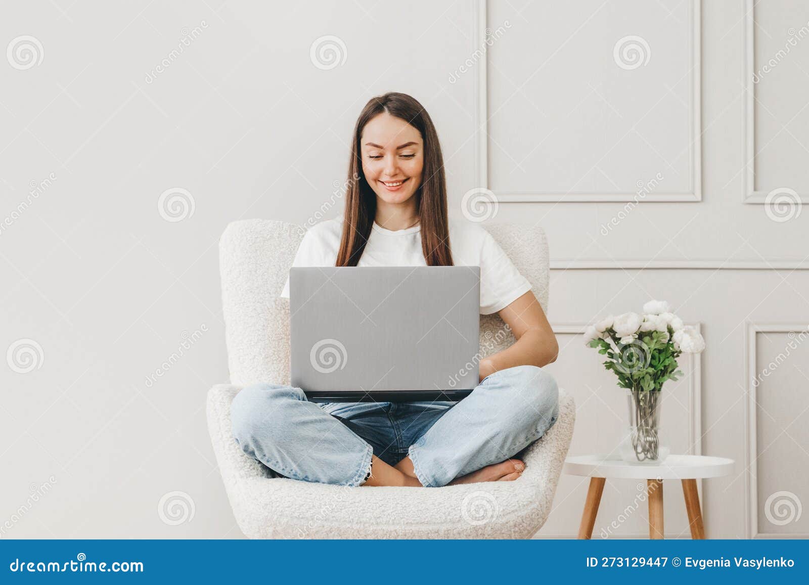 caucasian student girl sits in a chair uses a laptop and looks at the monitor screen