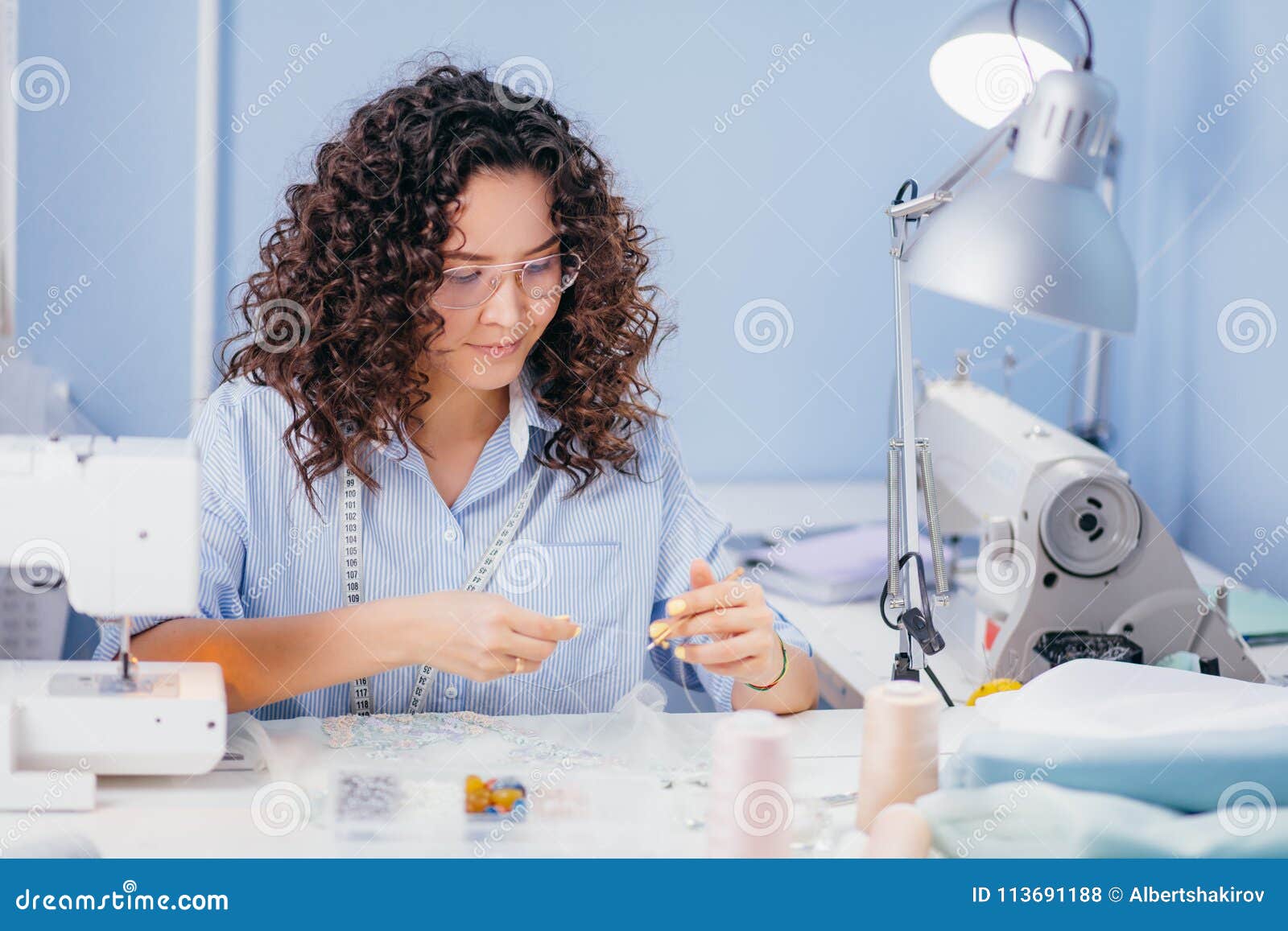 Caucasian Tailor Stretching Thread at Sewing Stock Photo
