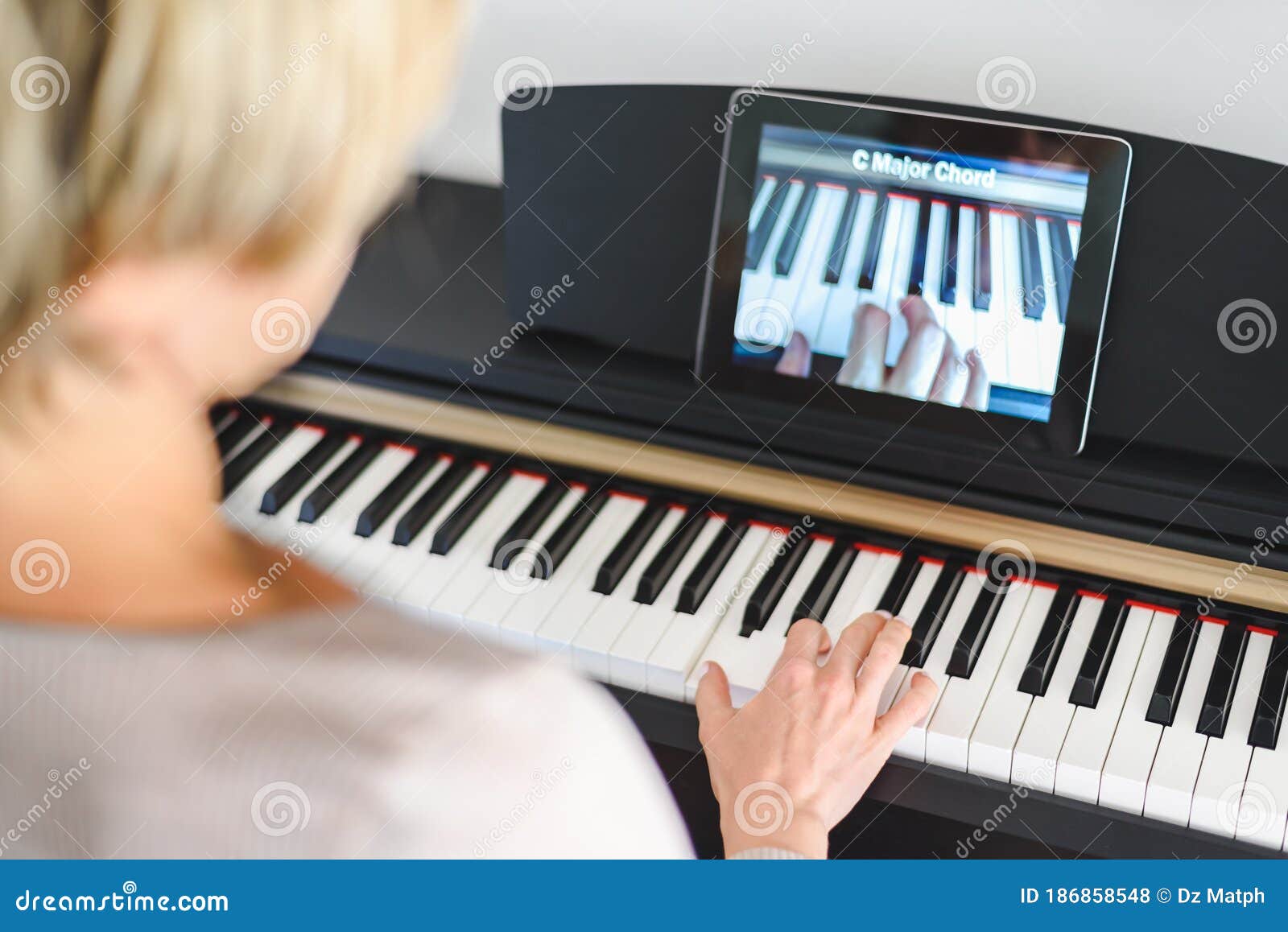 caucasian woman learning to play piano with video lessons.