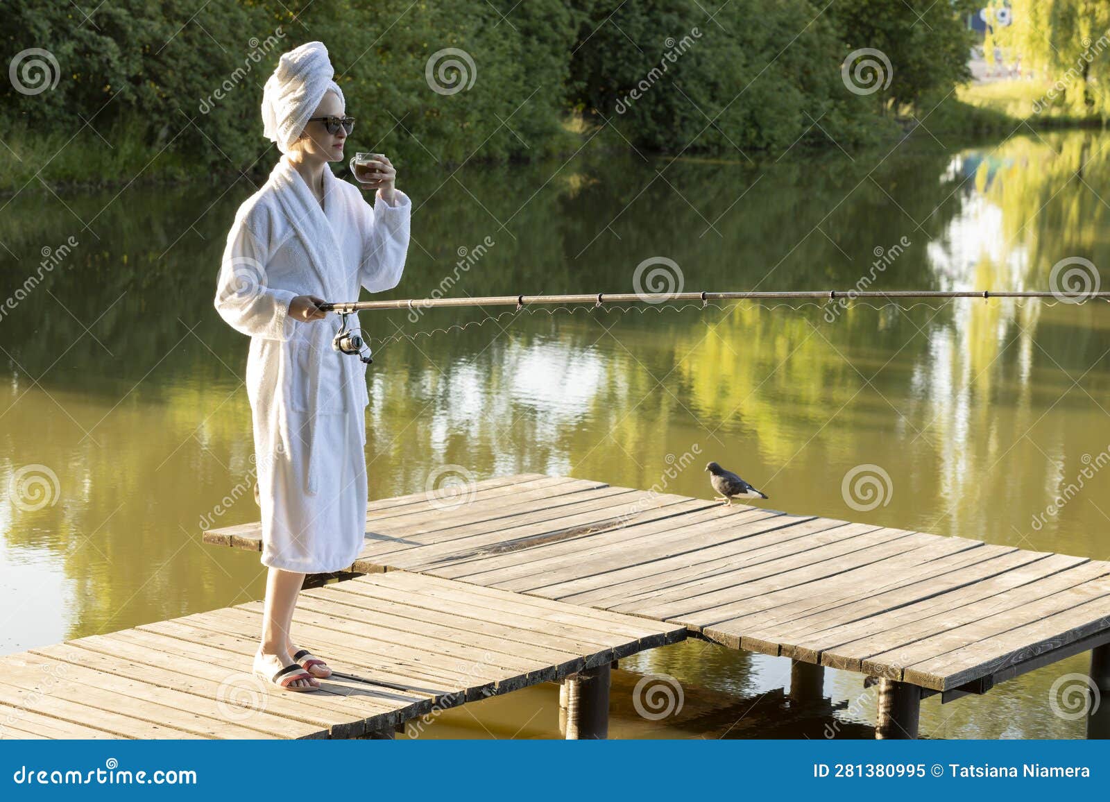 Caucasian Woman in White Robe and Towel is Fishing Holding