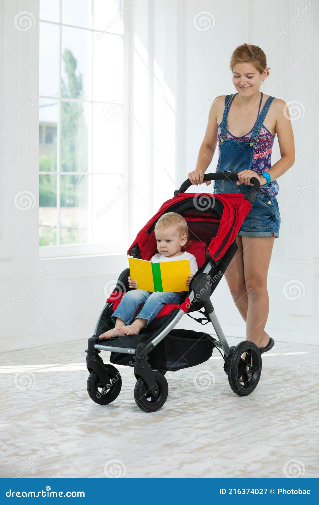 Caucasian Young Woman Pushing Stroller with Toddler Boy Indoors Stock ...