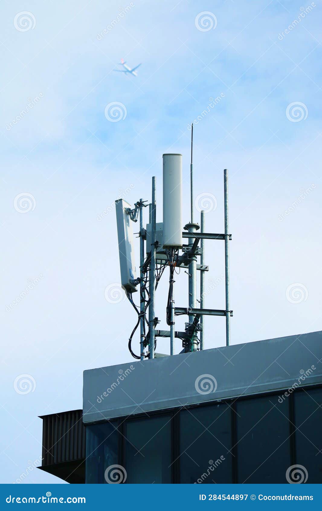 Cell Phone Antennas on the Rooftop with Airplane Flying on Sky Stock