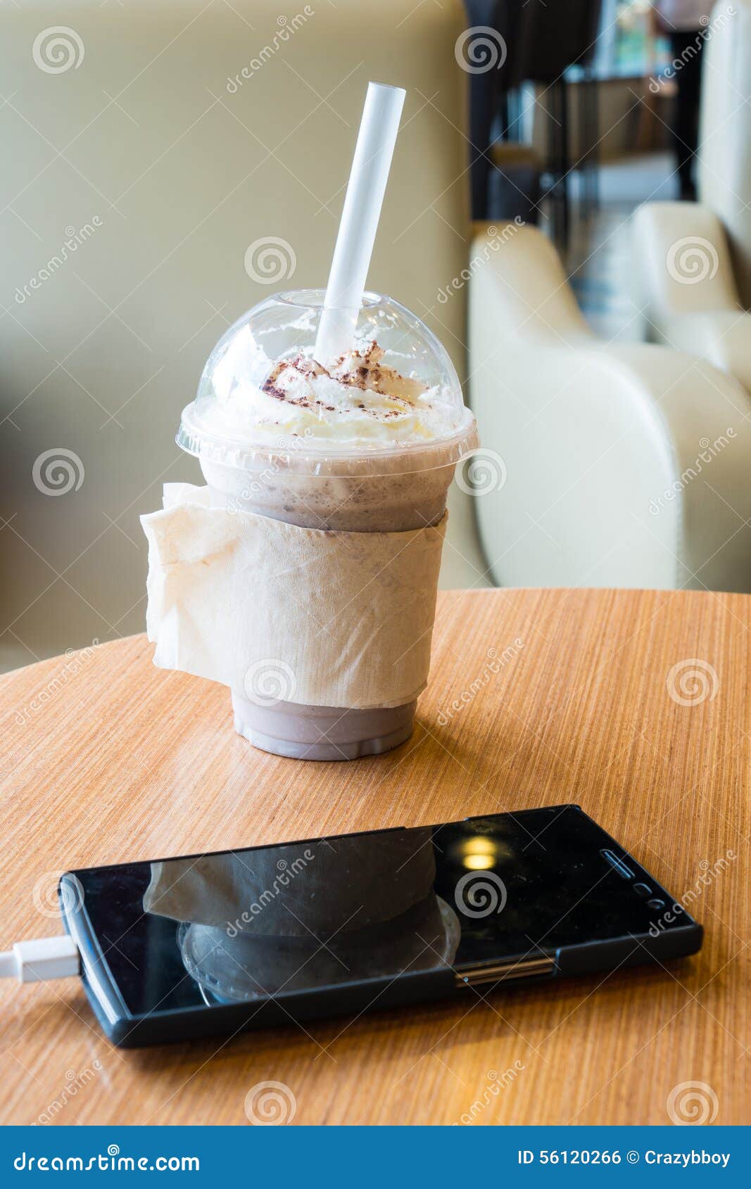 cell phone charging in the cafe with a plastic cup of iced chocolate frappe