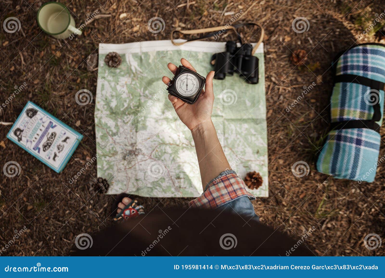 a girl is holding a compass to orientate in the forest with a map.