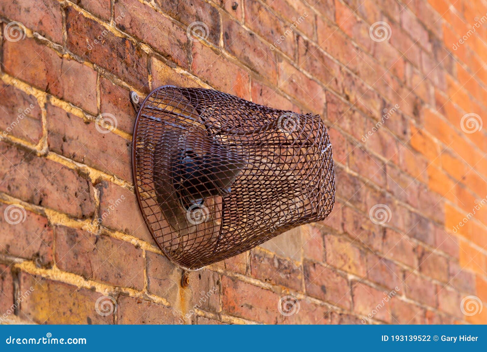 A Central Heating Extractor Pipe on the Outside of a House with a Rusty Metal Cage Around it