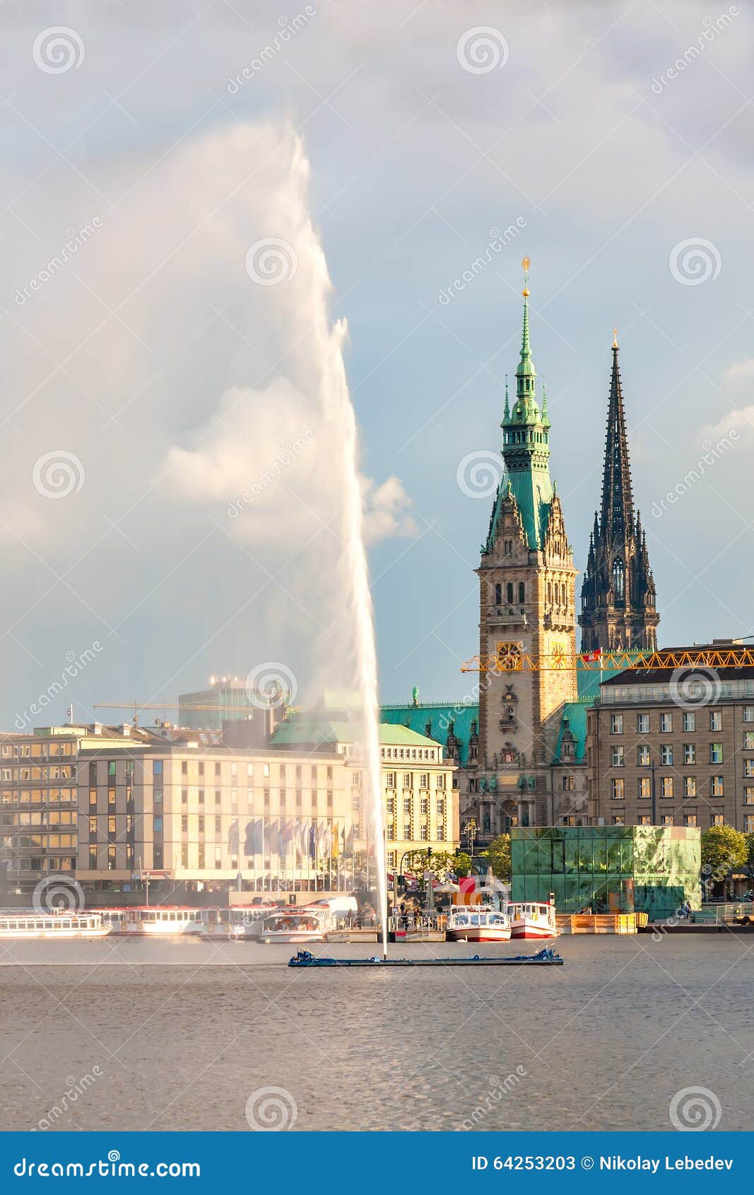 Centro de ciudad de Hamburgo del panorama con ayuntamiento y una fuente. Lago Alster con una fuente en el fondo el ayuntamiento y la catedral en la puesta del sol Los buques de pasajeros están en la litera Nubes oscuras en el cielo iluminado por el sol