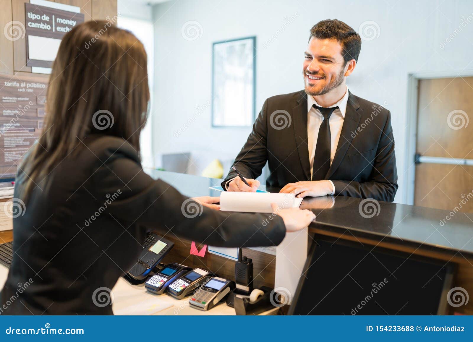 Ceo Making Reservation With Receptionist At Counter Stock Photo