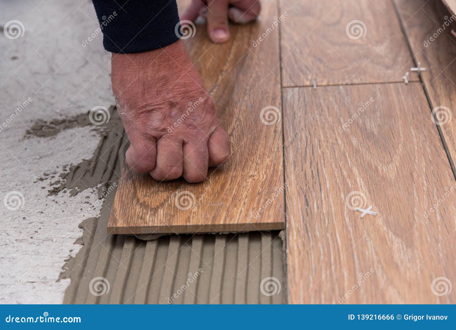 Worker Placing Ceramic Floor Tiles On Adhesive Surface Leveling