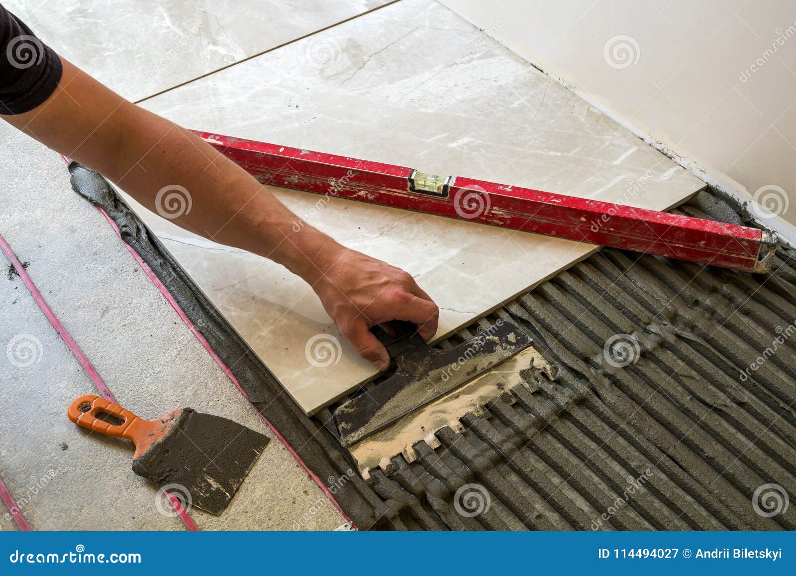 Ceramic Tiles and Tools for Tiler. Worker Hand Installing Floor Stock