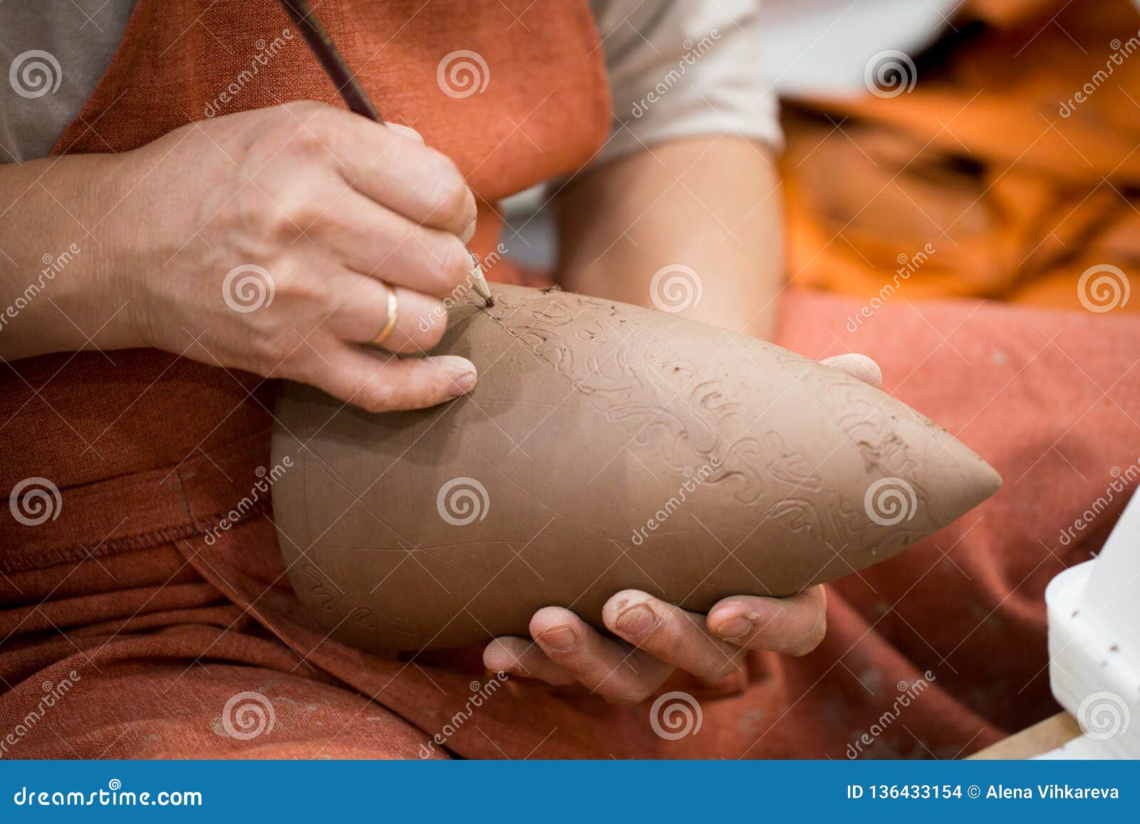 ceramic workshop, the master puts otnament on unfired earthenware jug. close-up of master hands. made by hand, a hobby. background