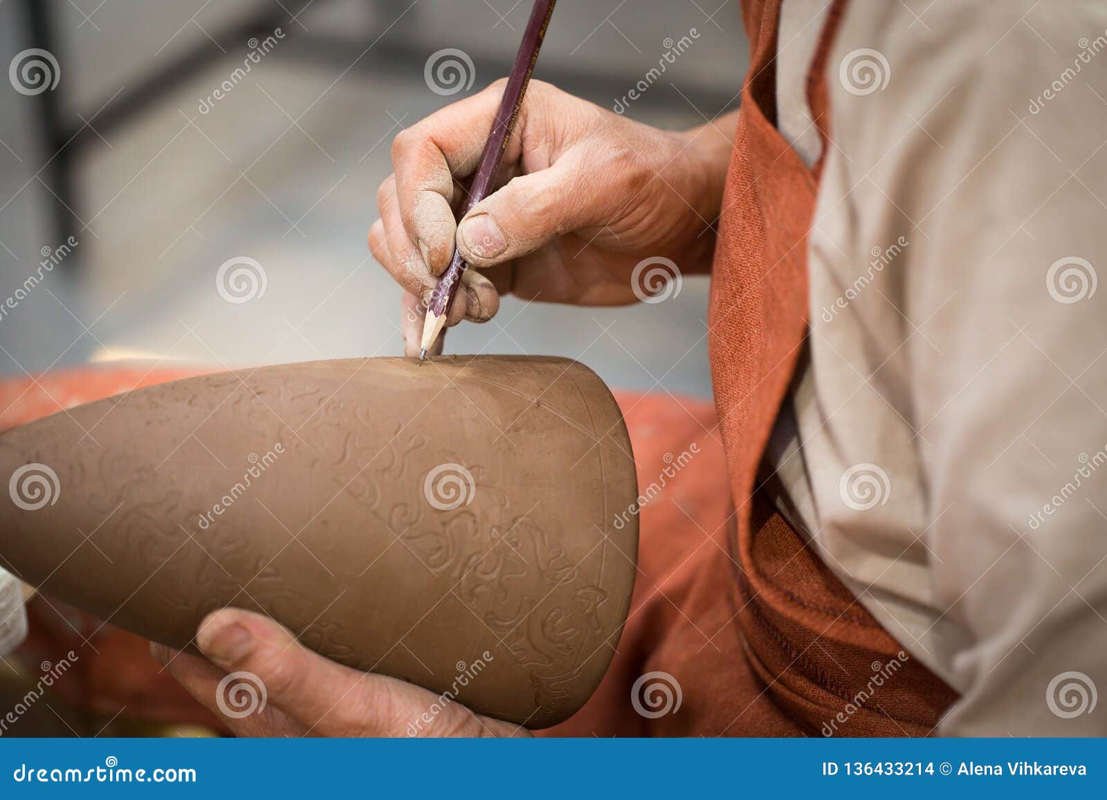 ceramic workshop, the master puts otnament on unfired earthenware jug. close-up of master hands. made by hand, a hobby. background