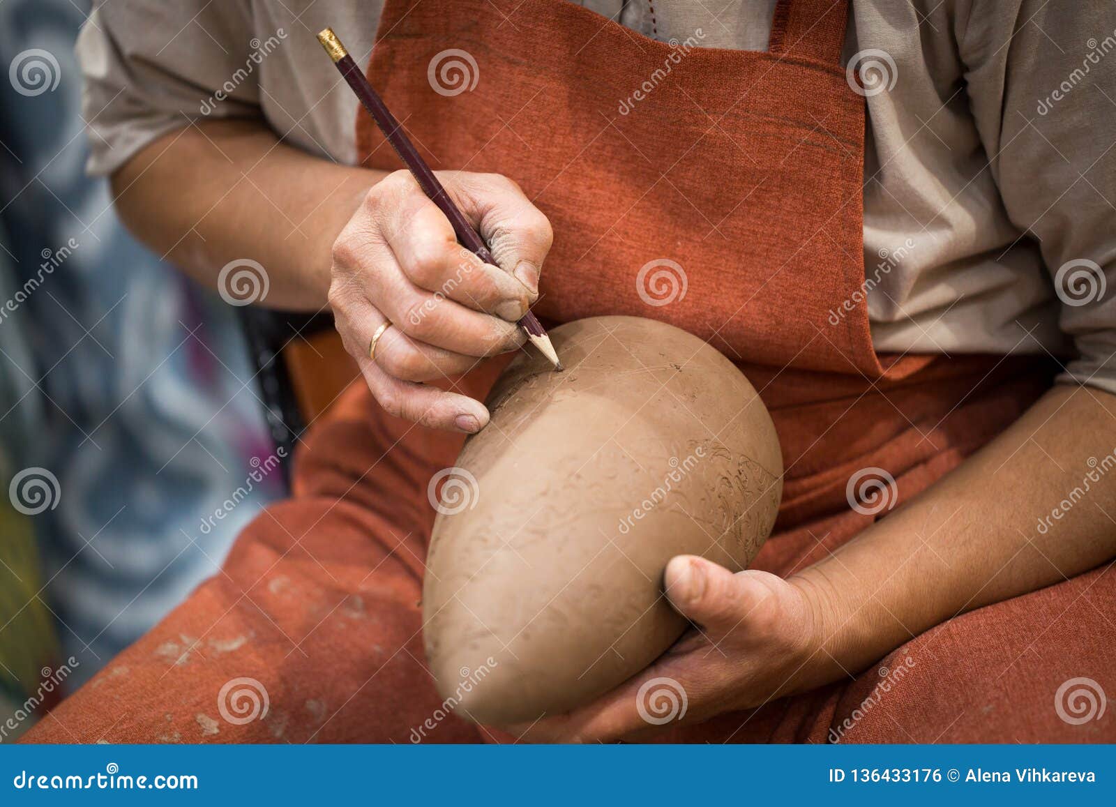ceramic workshop, the master puts otnament on unfired earthenware jug. close-up of master hands. made by hand, a hobby. background