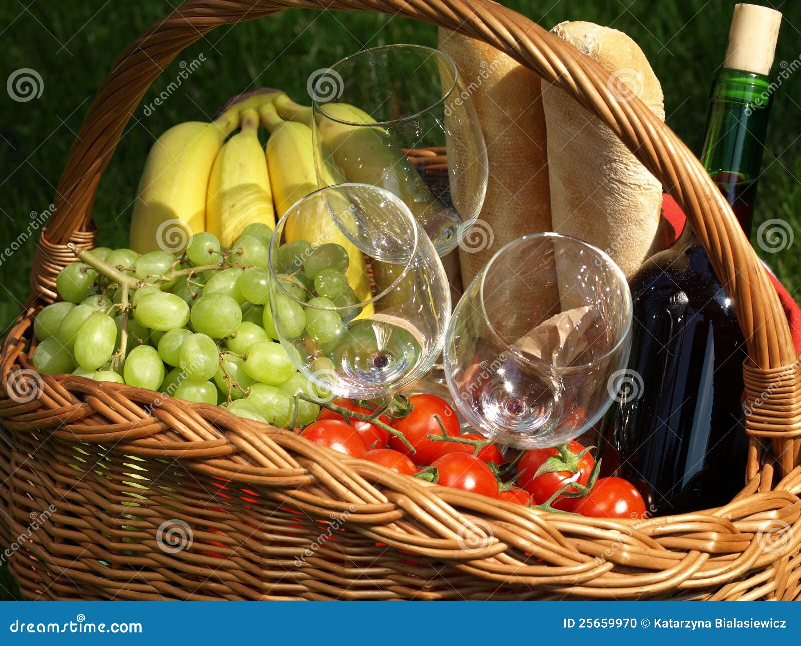 Cesta de la comida campestre con el vino, las uvas y los tomates