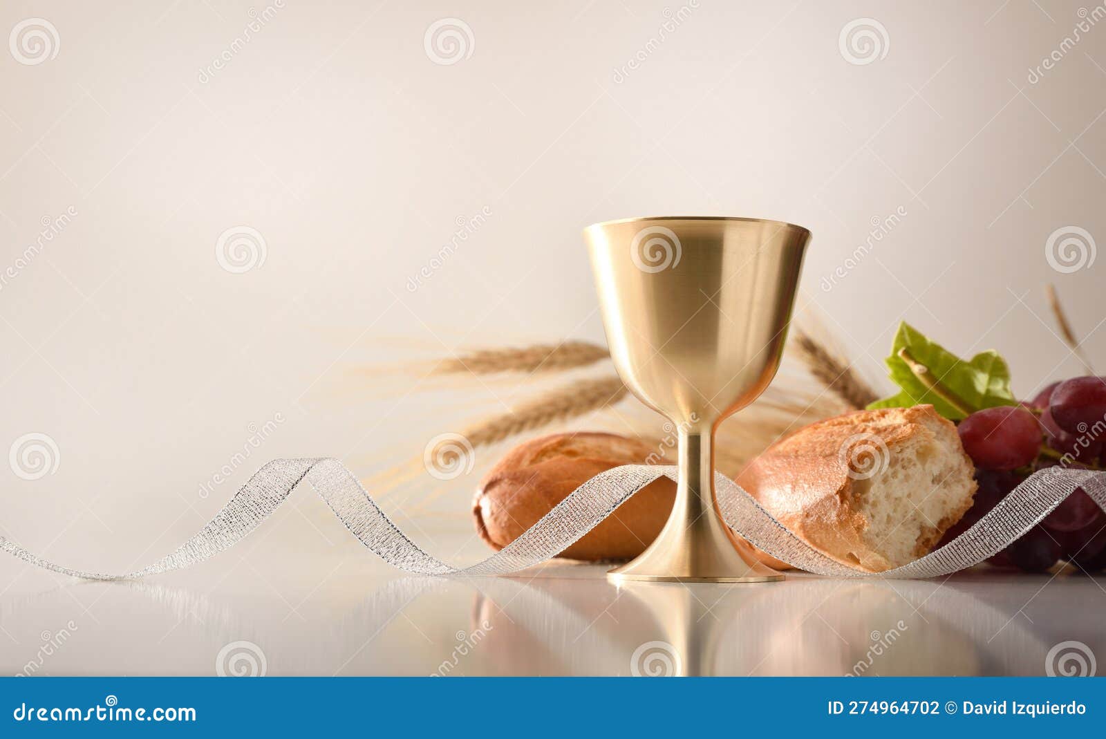 chalice on table with bread and grapes in the background