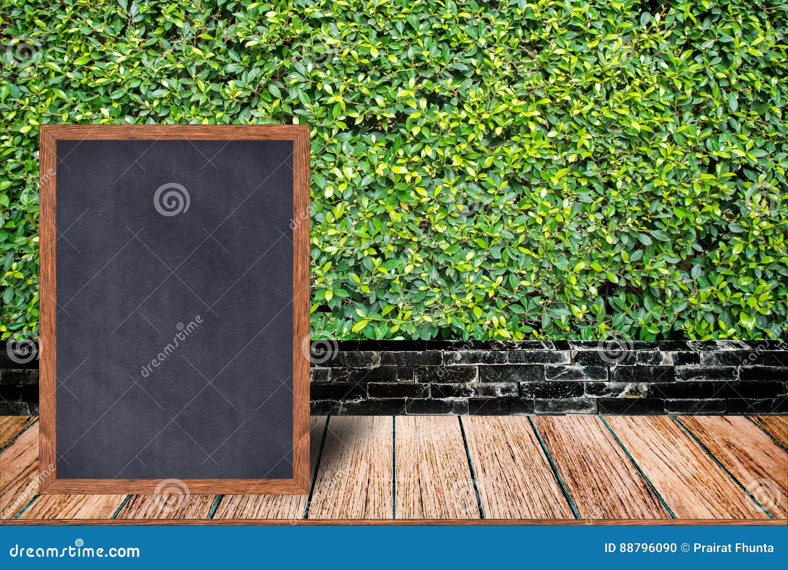 Chalkboard wood frame, blackboard sign menu on wooden table and grass wall background. Chalkboard wood frame, blackboard sign menu on wooden table and grass wall background with copy space, Template mock up for adding your design and leave space beside frame for adding more text.