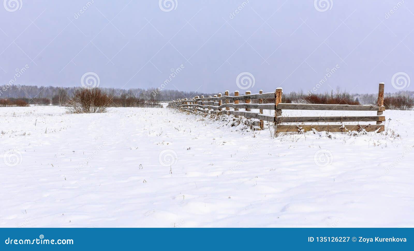 Champ couvert de neige dans la campagne Une barrière en bois des terres cultivables. Champ couvert de neige dans la campagne Barrière en bois sur le champ pour des buts agricoles