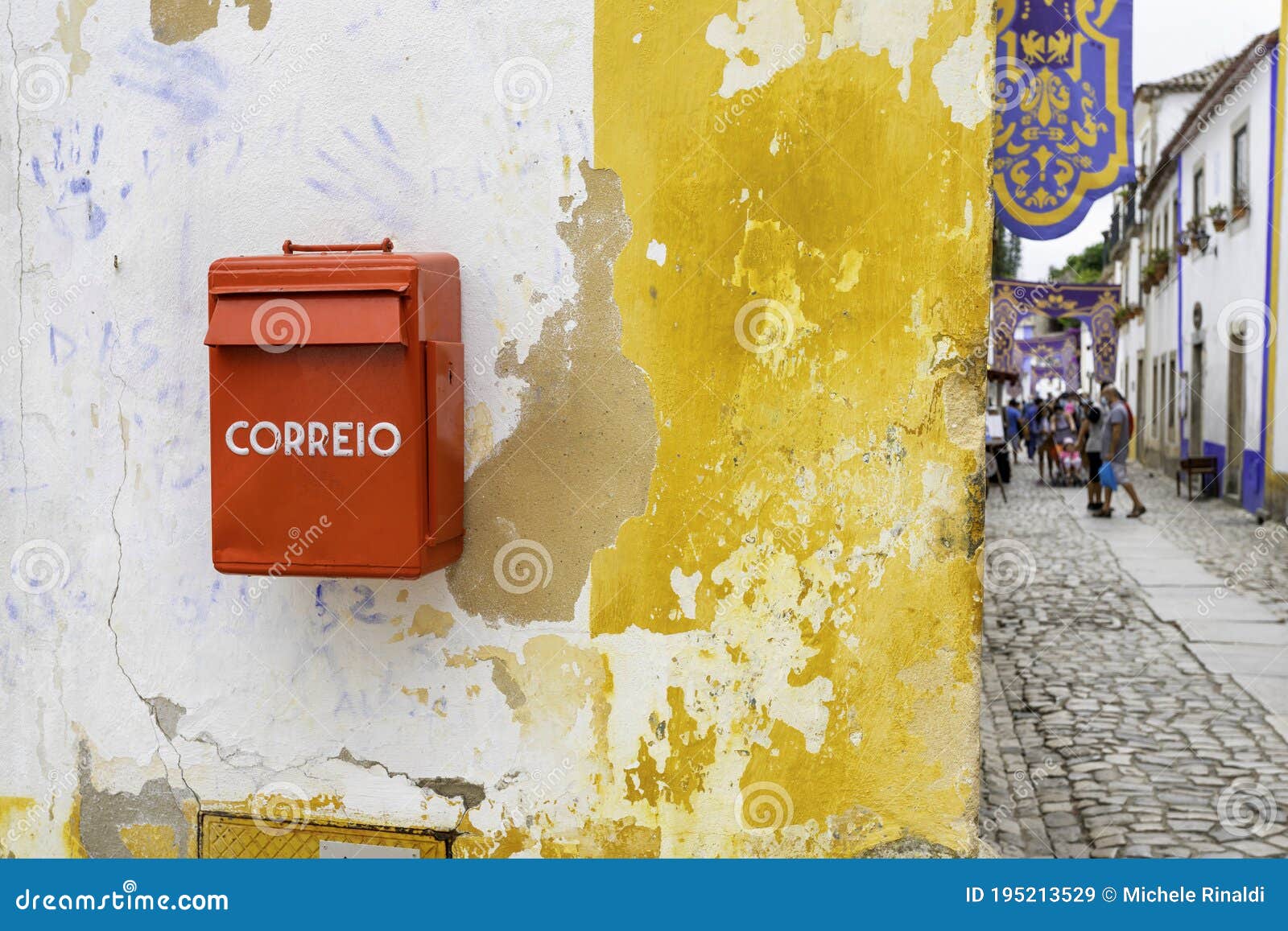 characteristic correio box in english: mail box in a little village in portugal. red mail box against a white and yellow