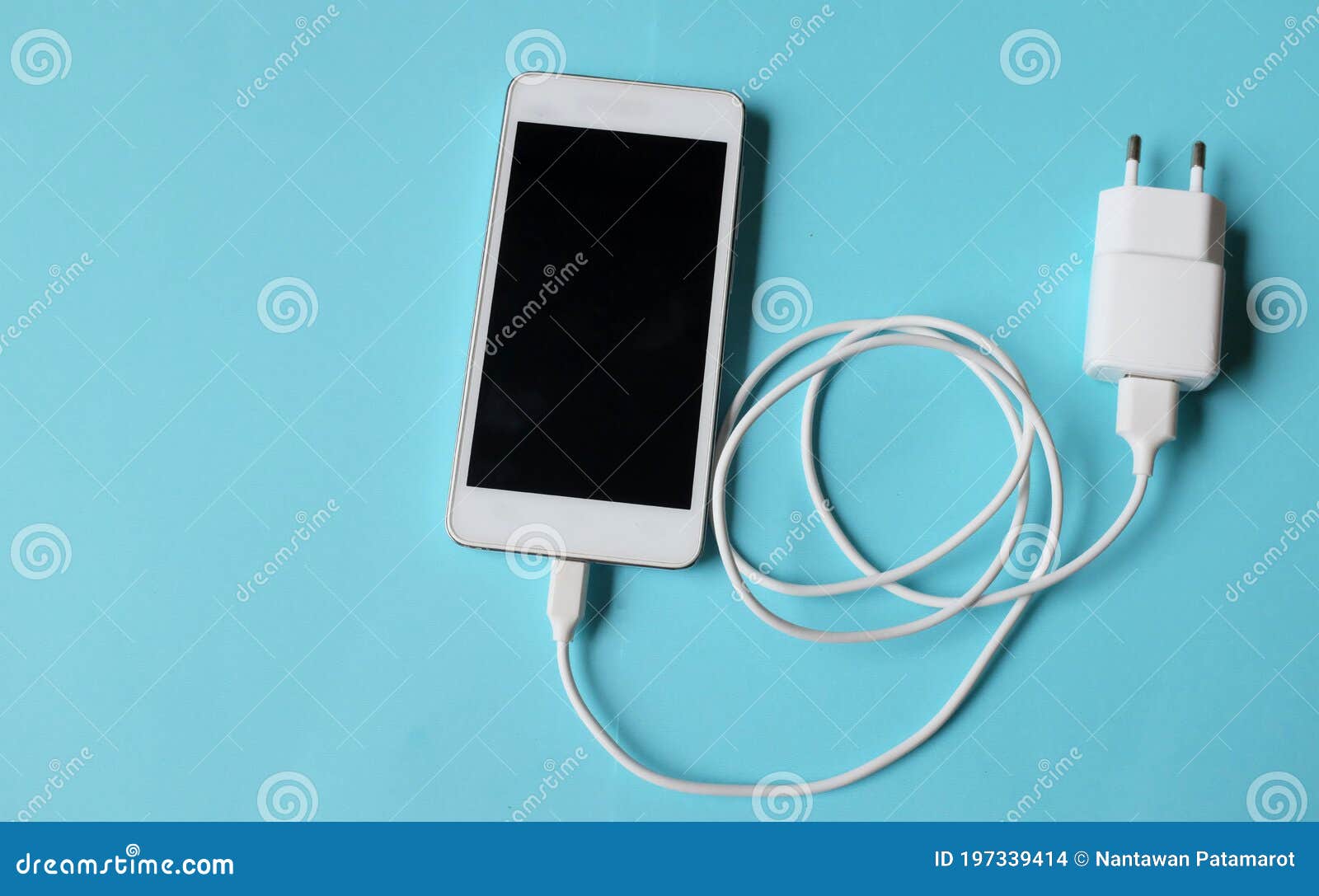 close up white smartphone plug in with charger adapter on blue background