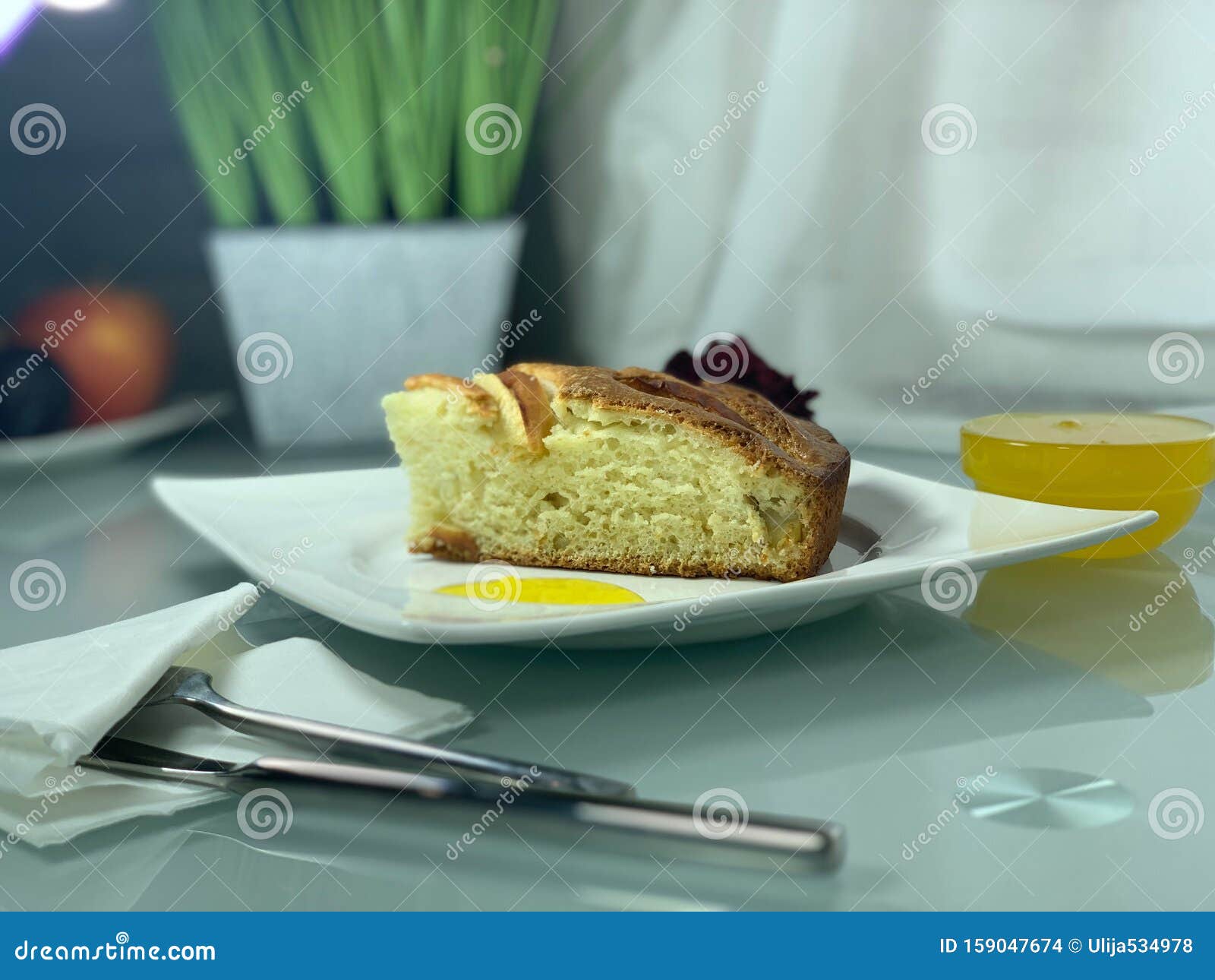 Charlotte äpple, på en vit platta Foderbestick Frukostinomhus Honung, dekorativa blommor på bordet