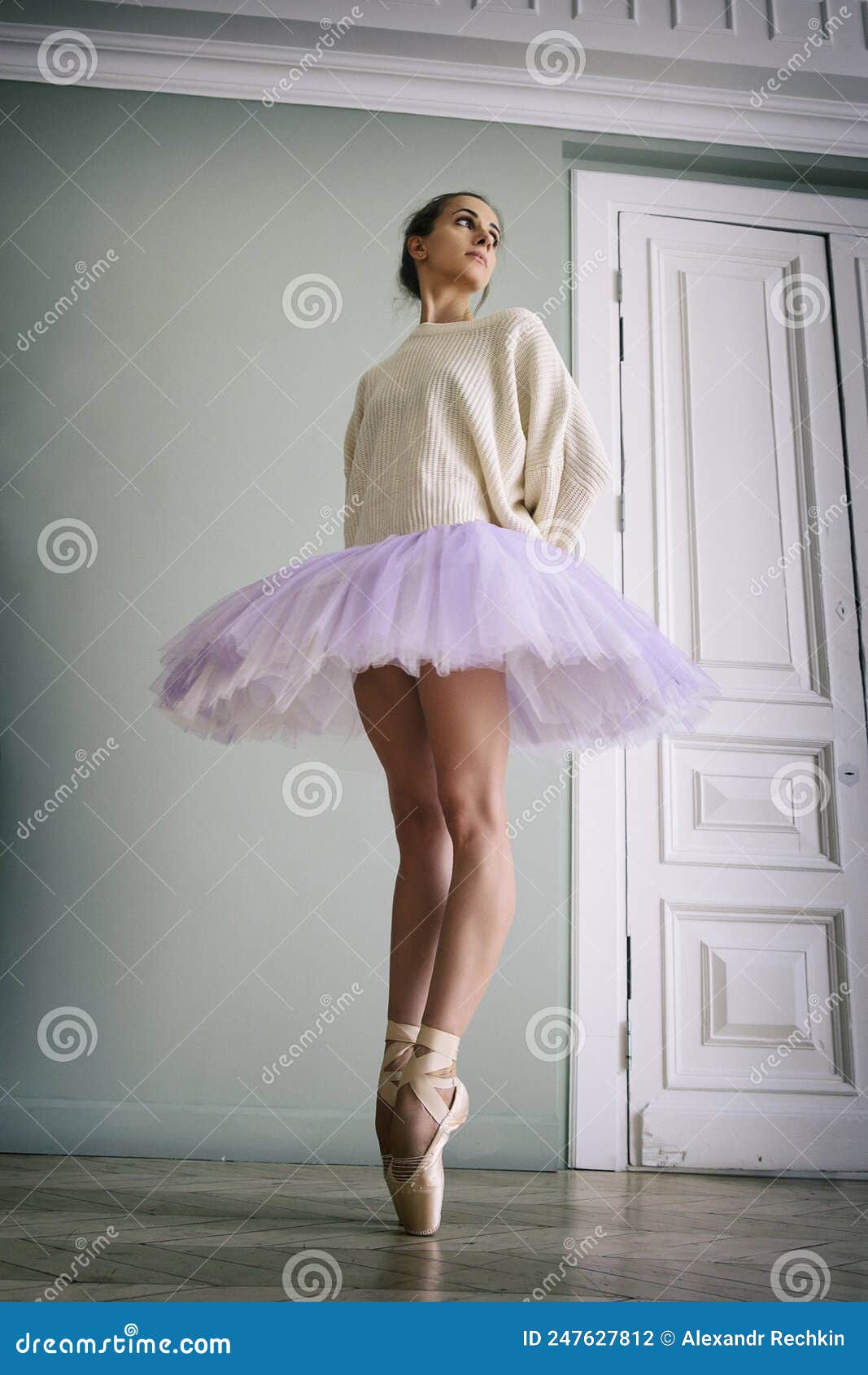 ballerina poses showing her legs in the room in front of the mirror in pointe shoes and tutu