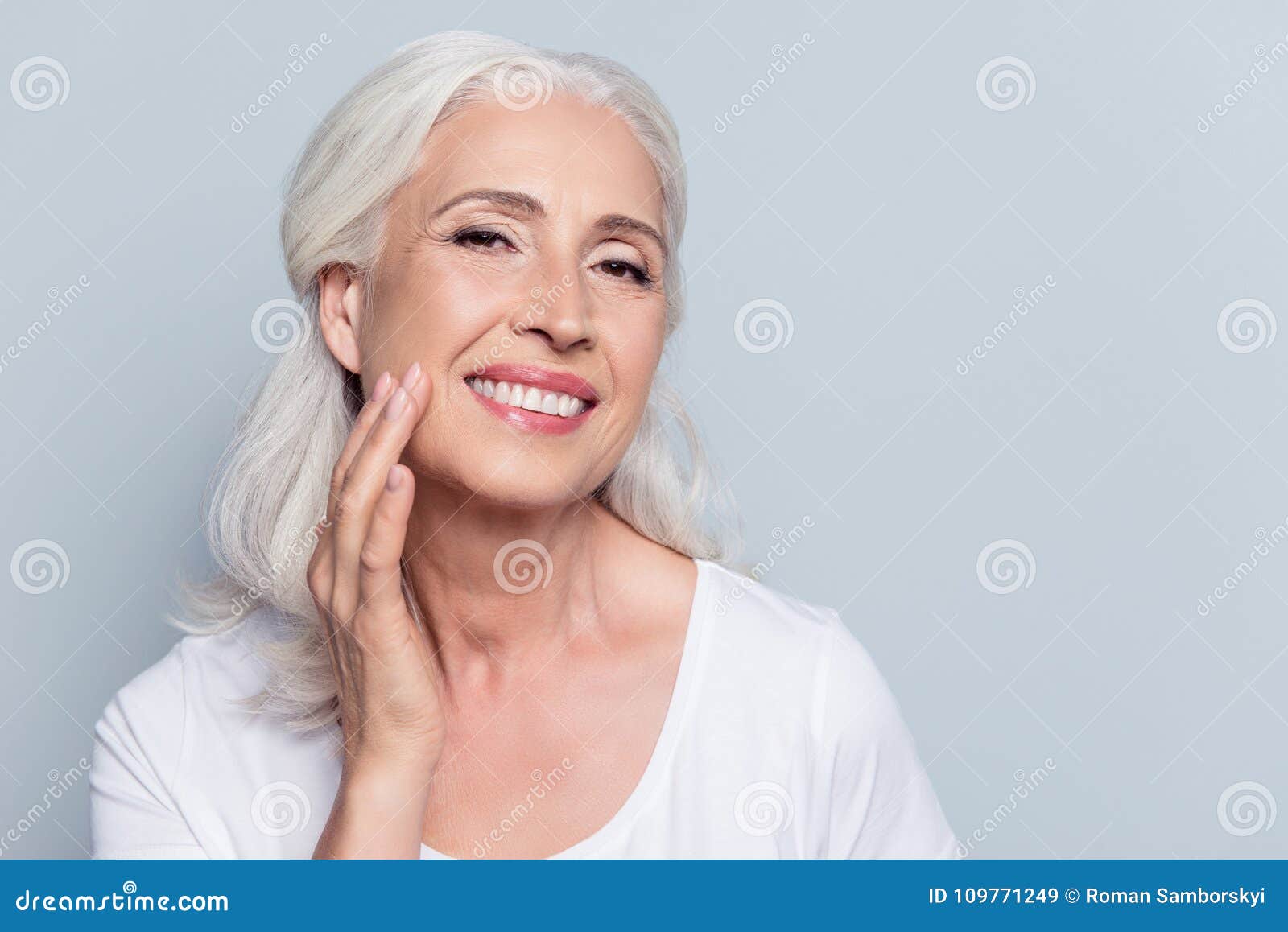 charming, pretty, old woman touching her perfect soft face skin