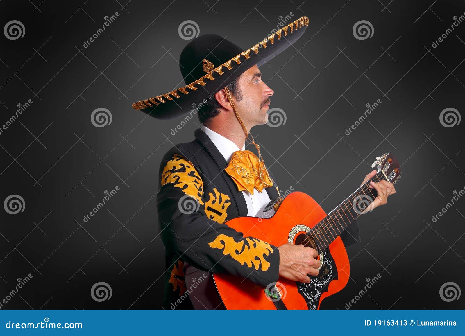 charro mariachi playing guitar on black