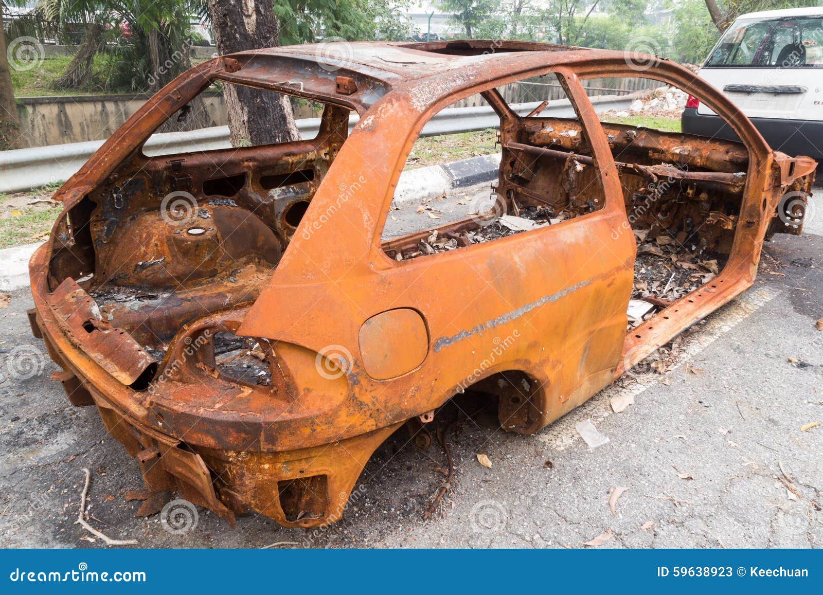 Chasis oxidado de un coche quemado abandonado por el lado de la calle