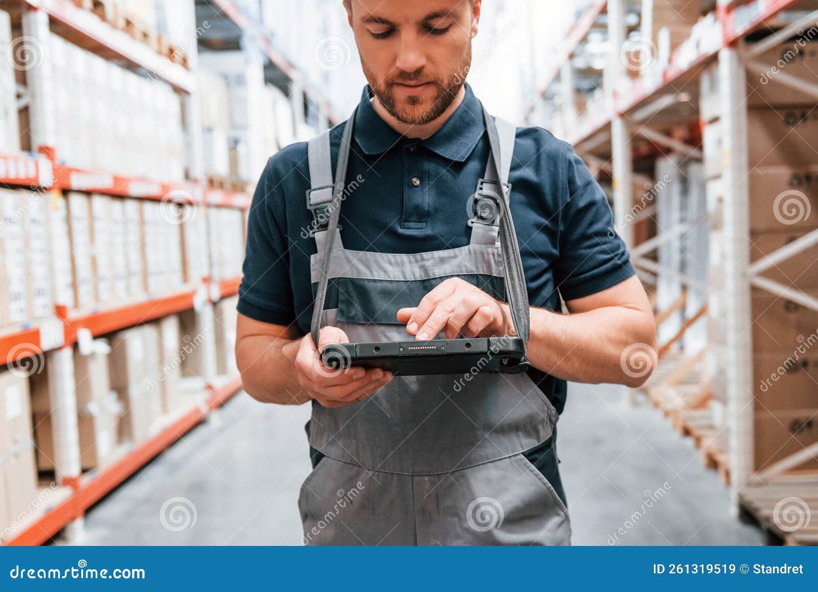 Checking Data in the Tablet. Employee in Uniform is Working in the