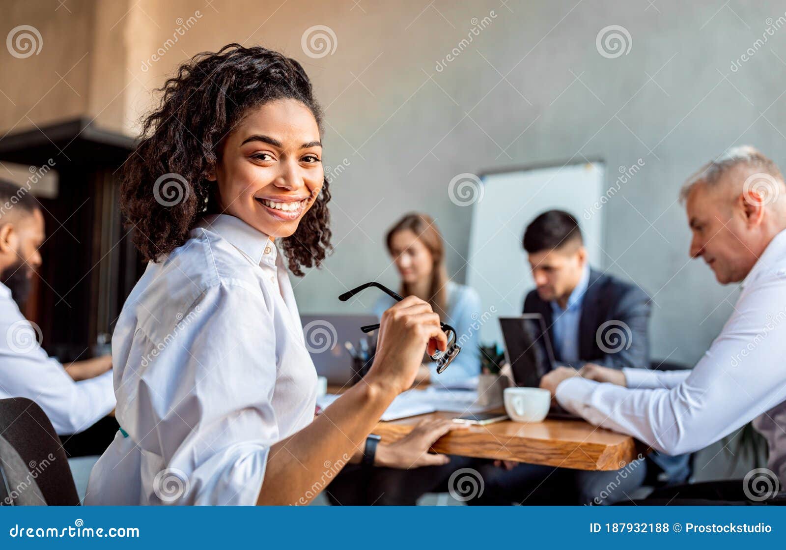 cheerful african businesswoman sitting with business partners in modern office