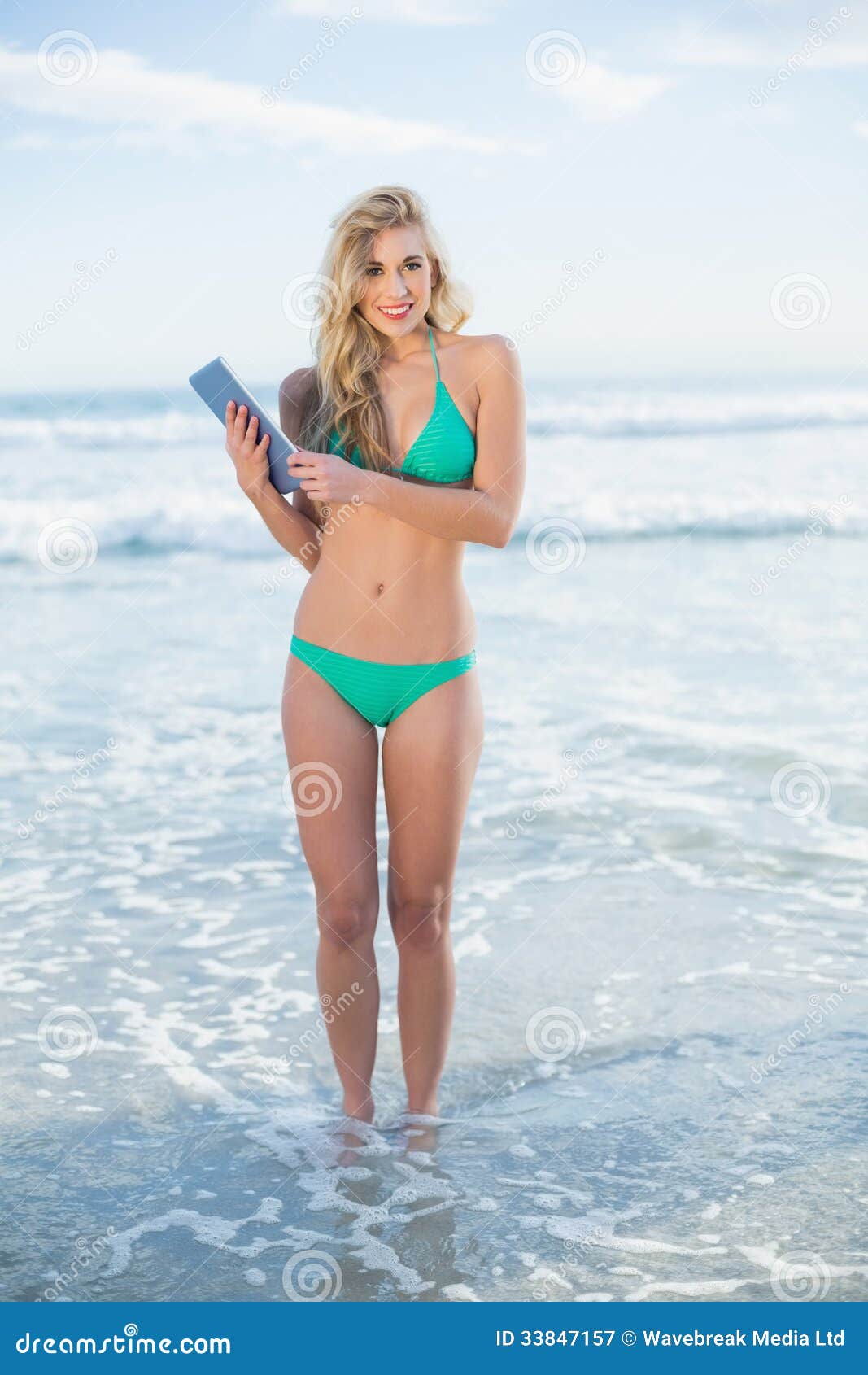 Cheerful Blonde Model in Green Bikini Holding a Tablet Pc Stock Image