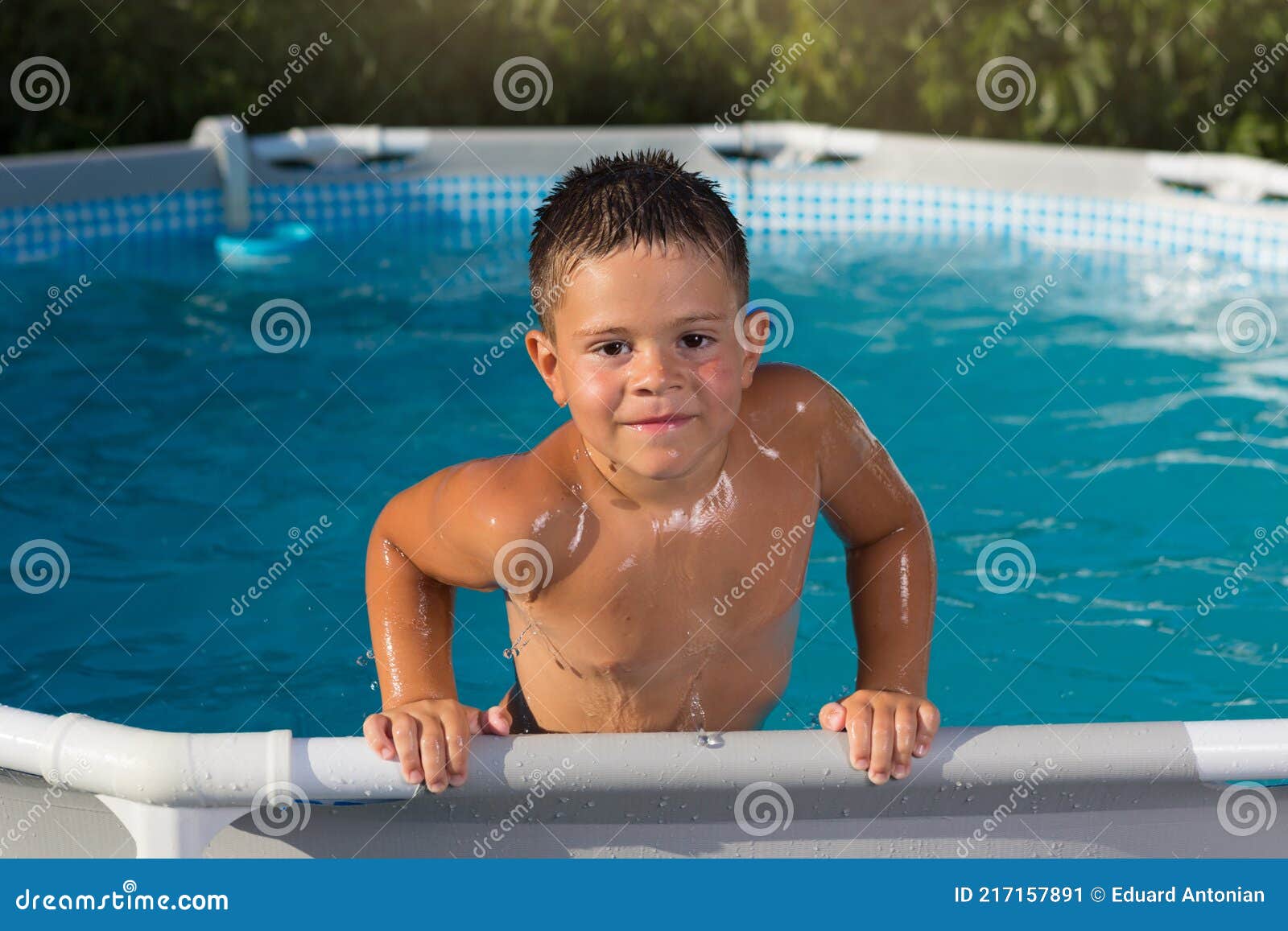 Cheerful Boy Climbs Out of the Pool, Leaning on the Edge of the Side