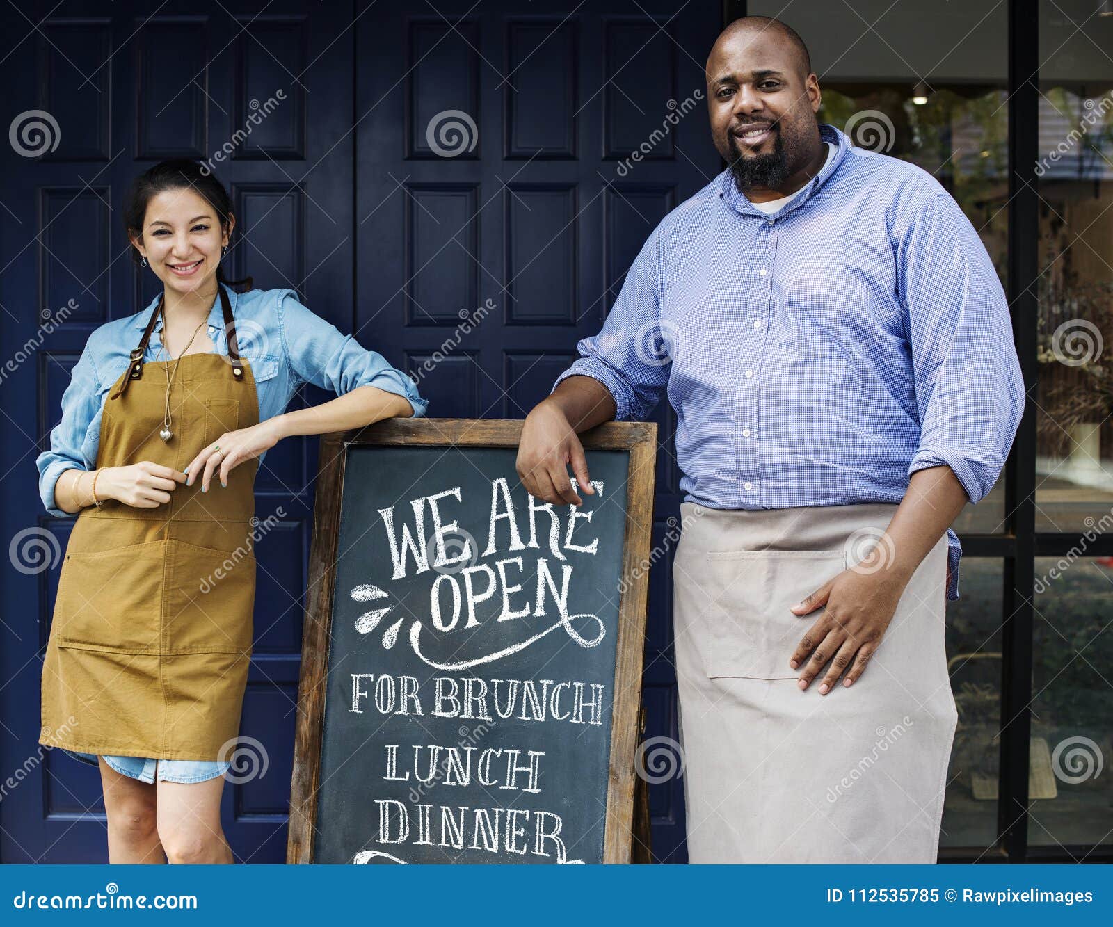 cheerful business owners standing with open blackboard