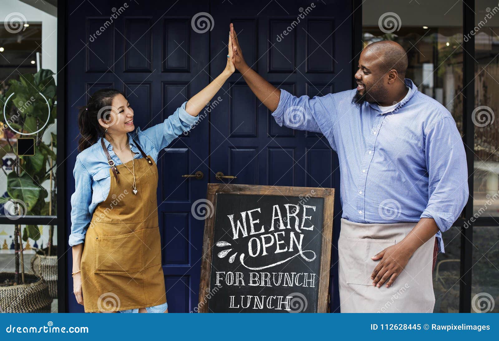 cheerful business owners standing with open blackboard
