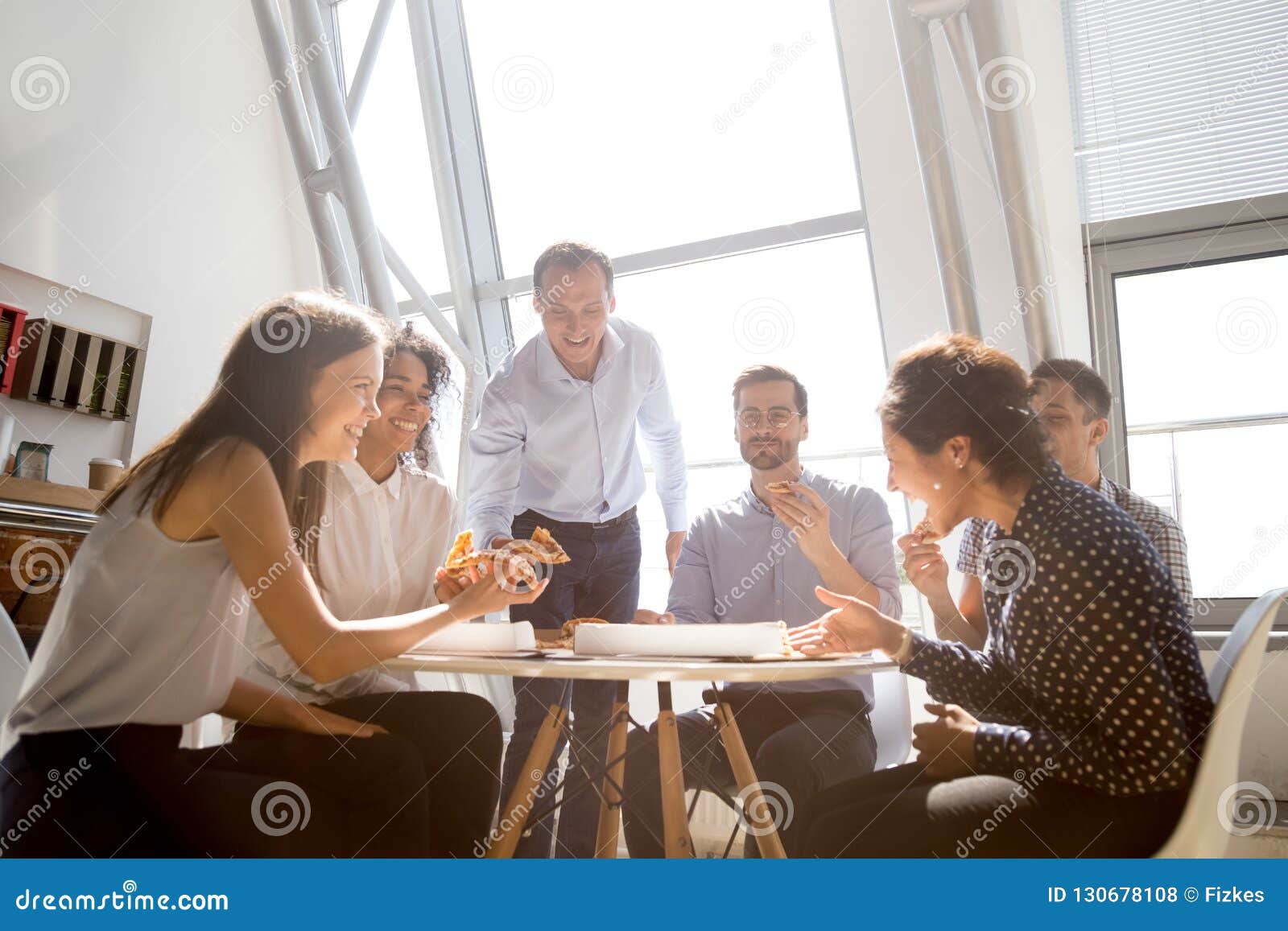 cheerful diverse team people laughing at joke eating pizza toget