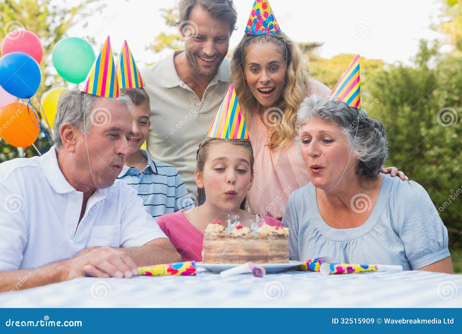 Cheerful Extended Family Watching Girl Blowing Out ...