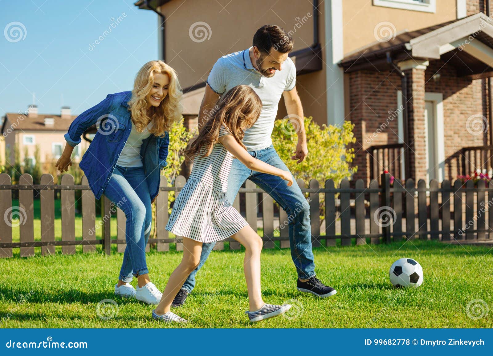 cheerful family playing football backyard lawn energetic pastime upbeat happy green their running towards ball 99682778