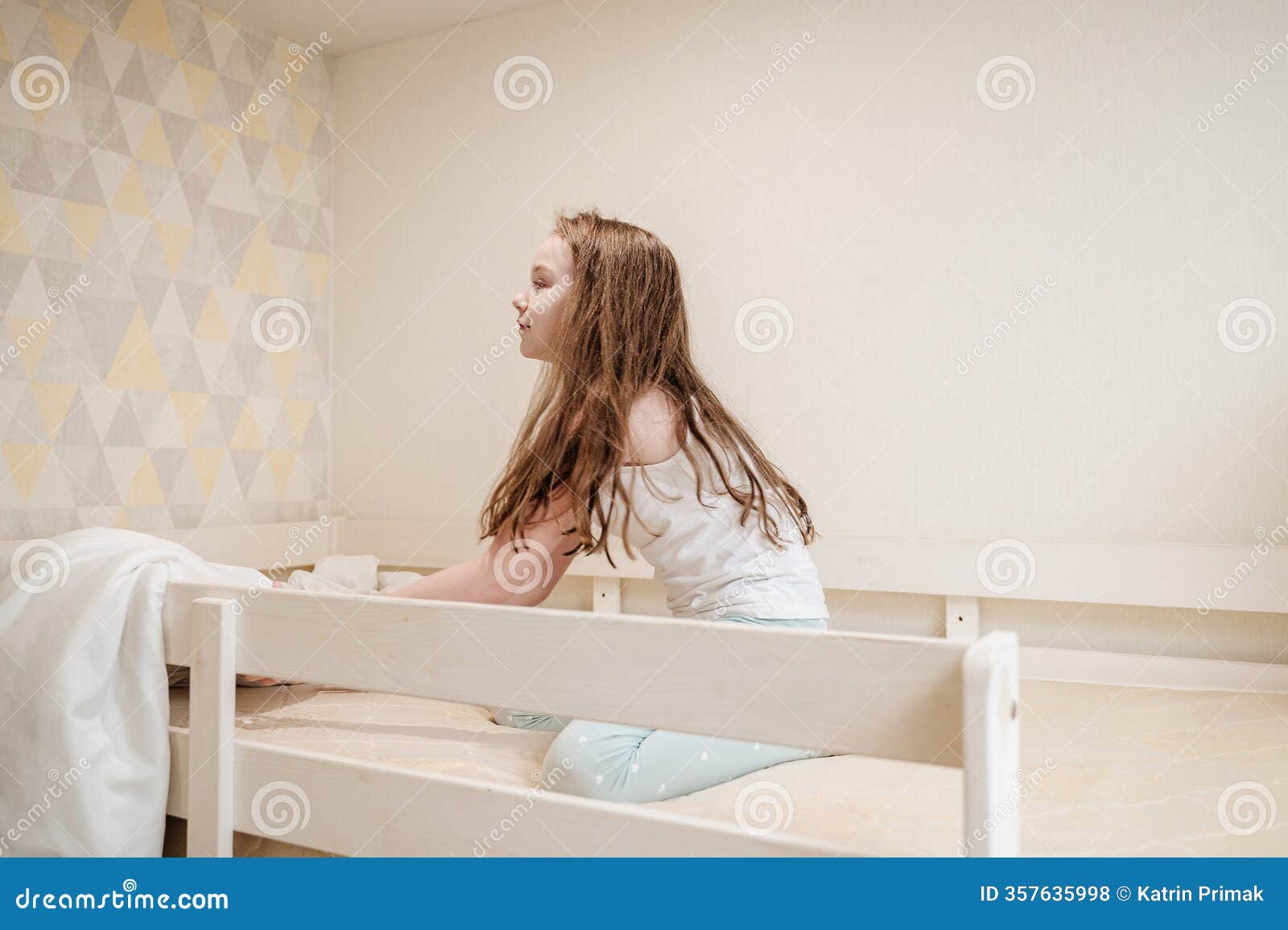 cheerful girl playing on a bed covered with a soft blanket, ideal for themes of childhood, comfort, home, joy, and cozy