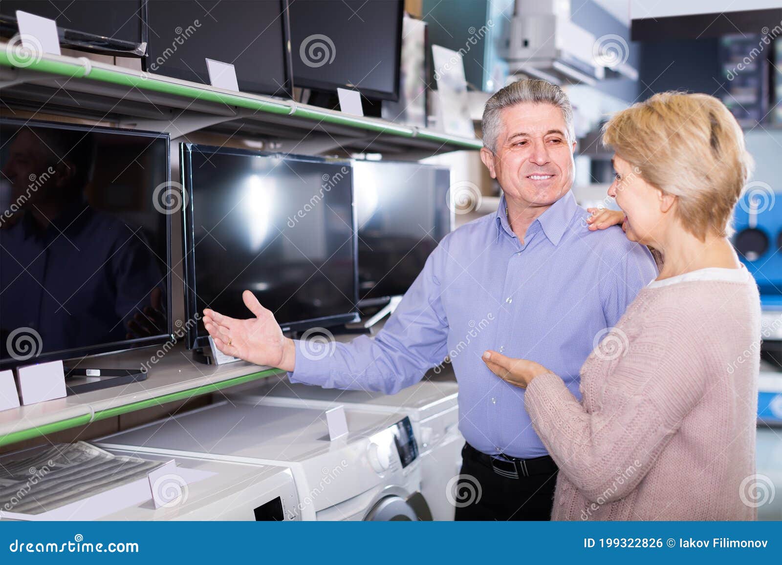 cheerful husband and wife choose for themselves tv in center of electronics