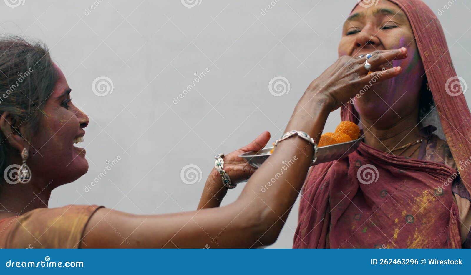 cheerful indian female is sharing a roundball of indian sweet dessert called laddo or lado